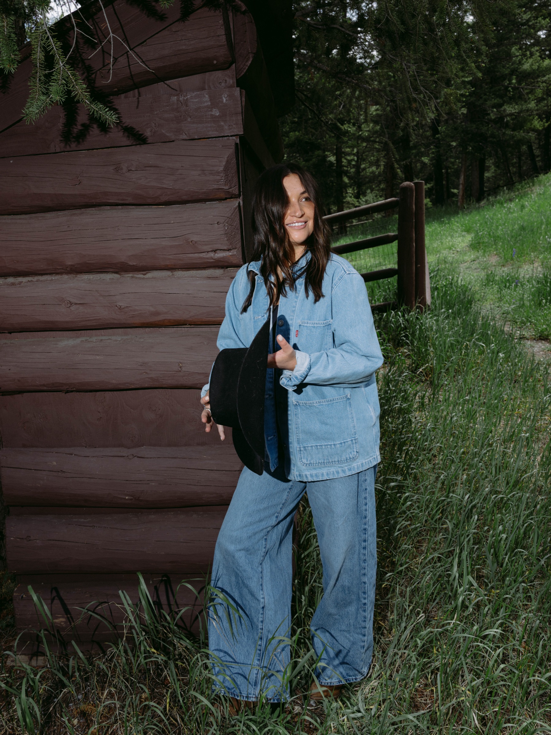 Model leaning against a log cabin in the Colorado forest