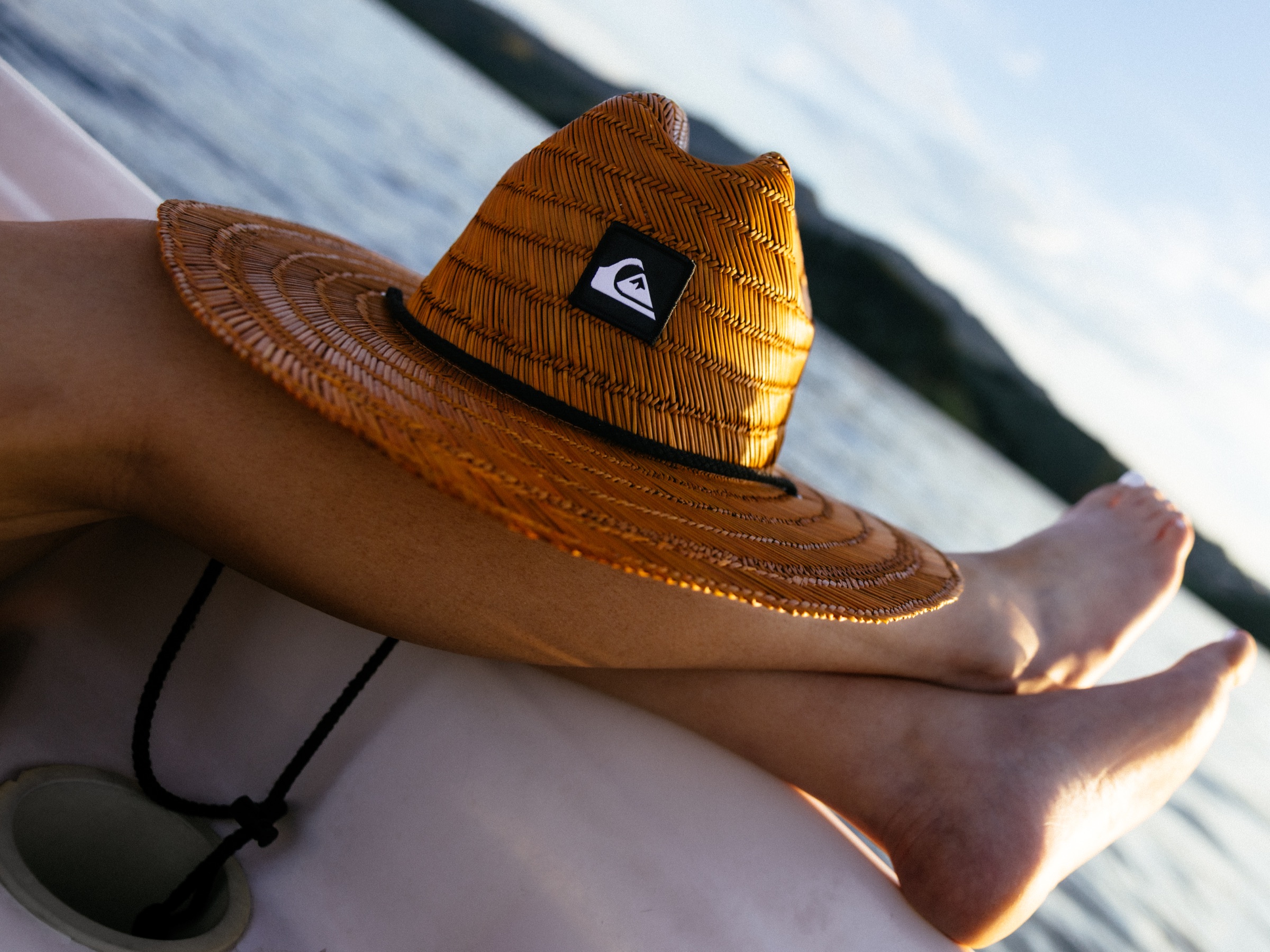 Quiksilver straw hat resting on someone's legs, the reservoir stretching out behind them