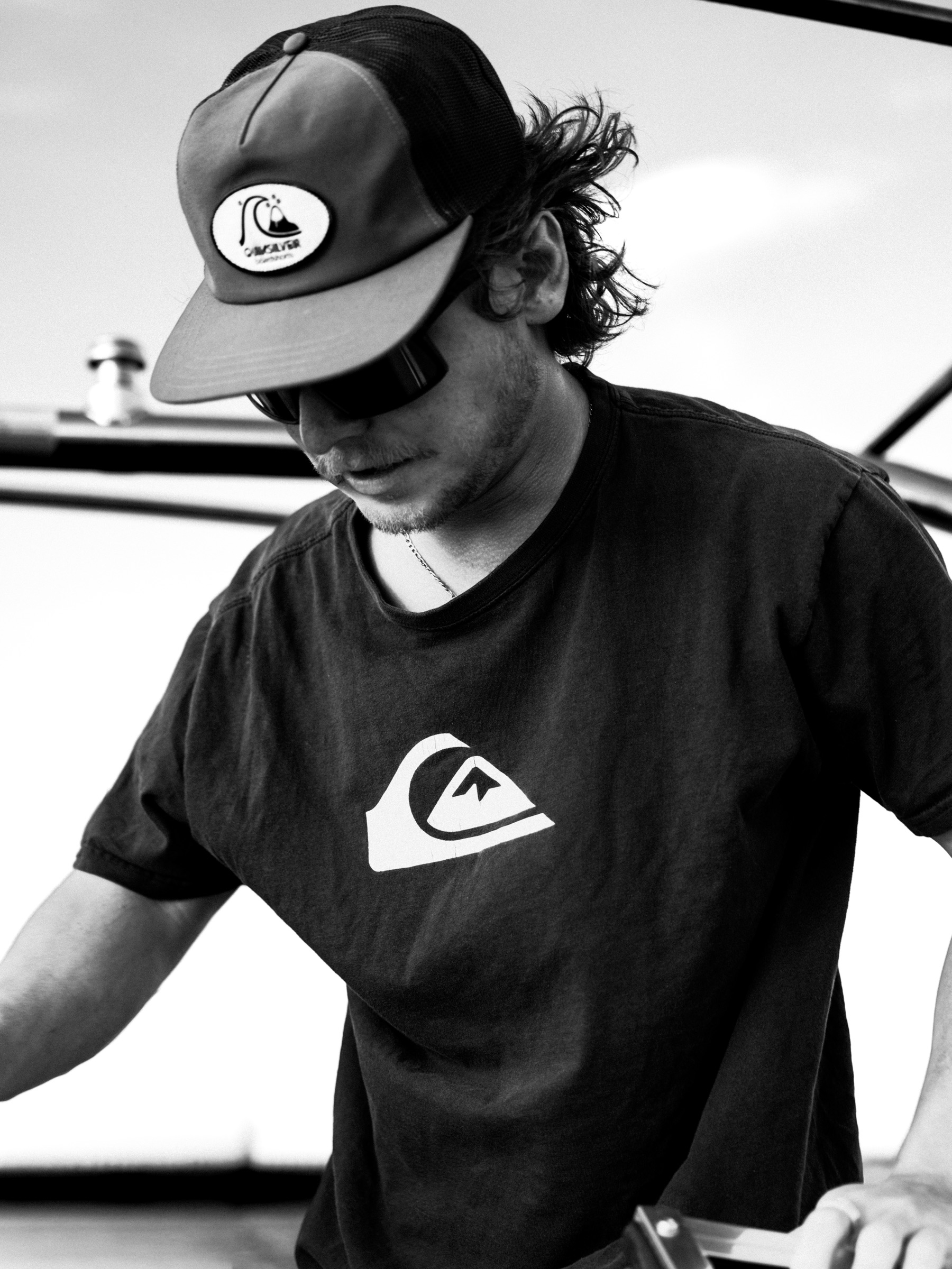Black and white — man in Quiksilver hat and tee, light behind him
